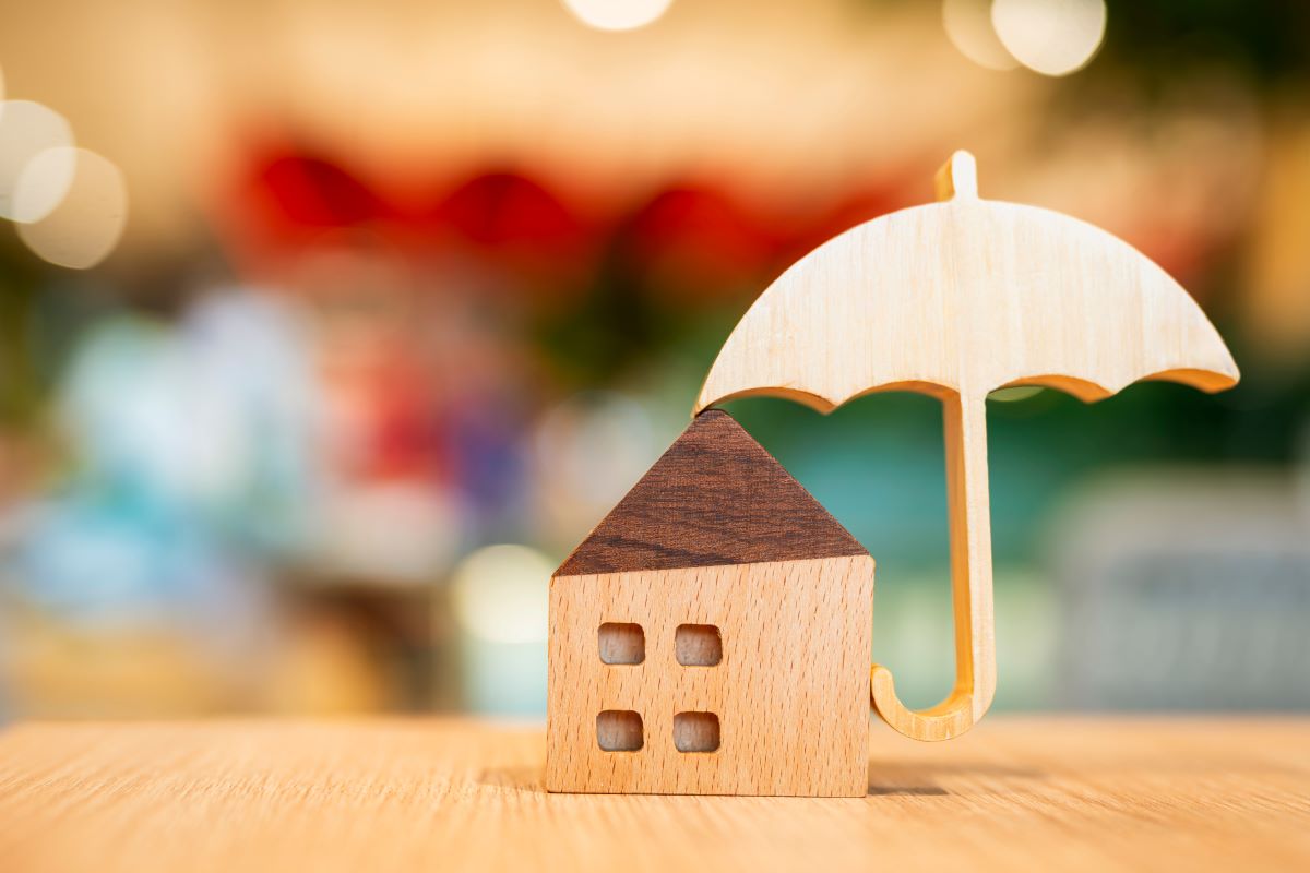 Wooden house model protected by a wooden umbrella on a wooden table