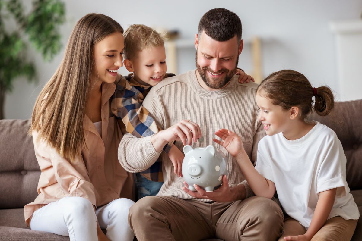 Smiling family putting away money in a piggy bank 